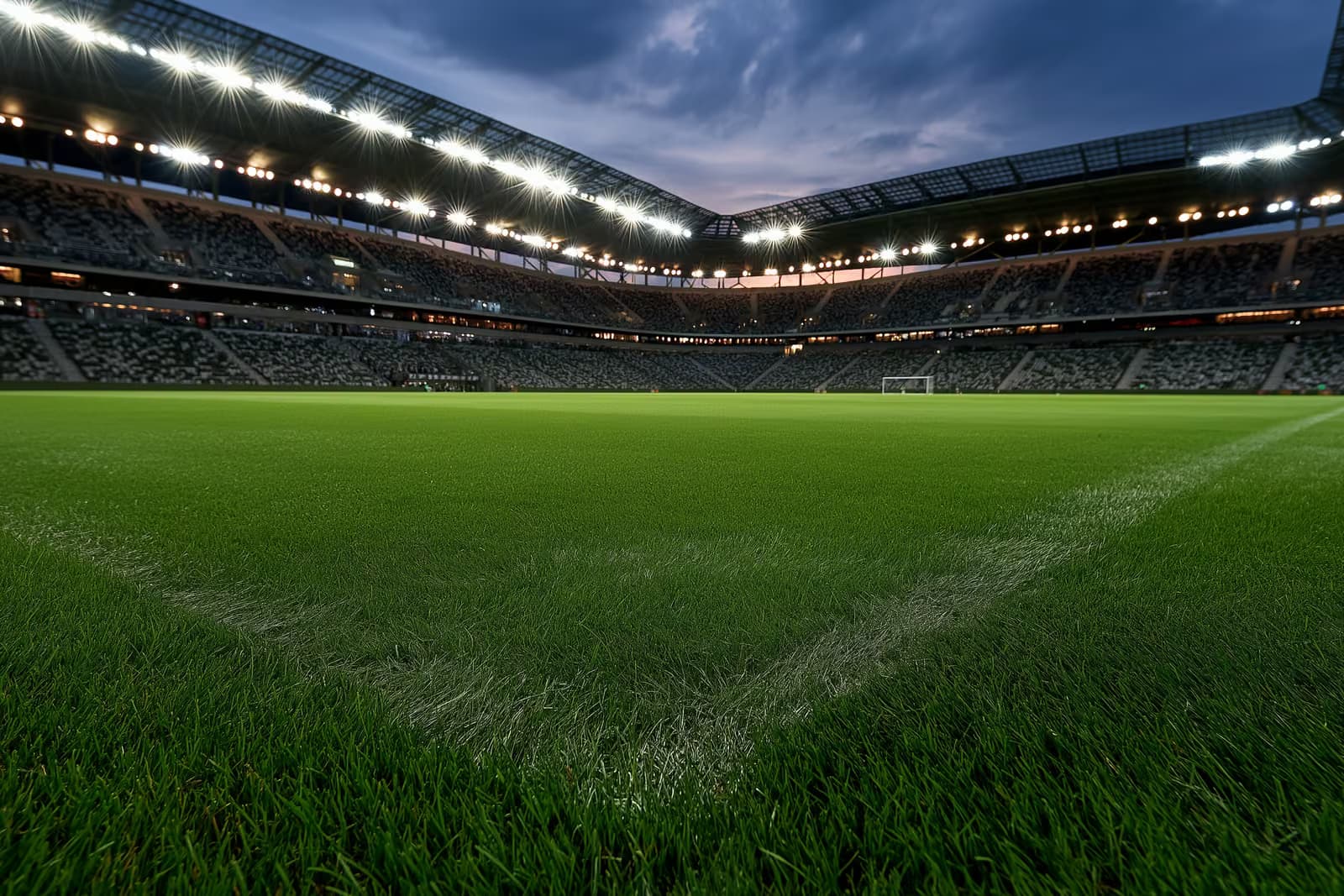 Oświetlony stadion piłkarski o zmierzchu przed wieczornym meczem.